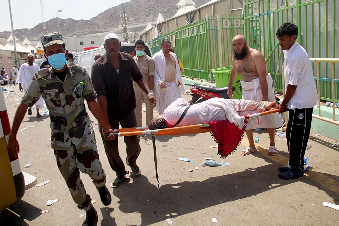朝圣者和沙特急救人员合力抬送躺在担架上的女子往医院。摄 : AFP