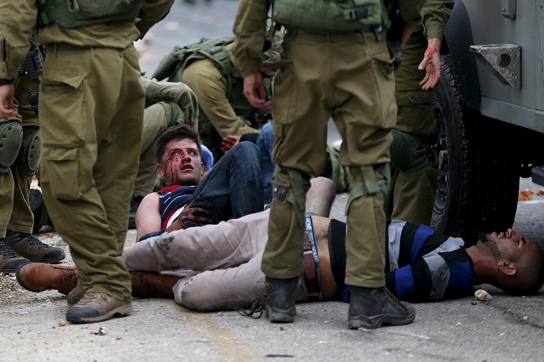 2015年10月7日，約旦河西岸，以色列軍人扣留一名在衝突中受傷的巴勒斯坦男子。攝：Mohamad Torokman/REUTERS