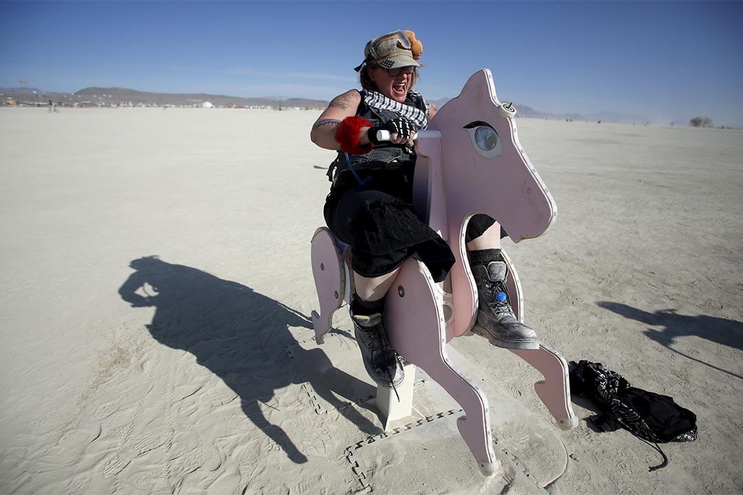 Burning Man（火人祭）中一个参加者骑着木马艺术装置。摄：Jim Urquhart/Reuters