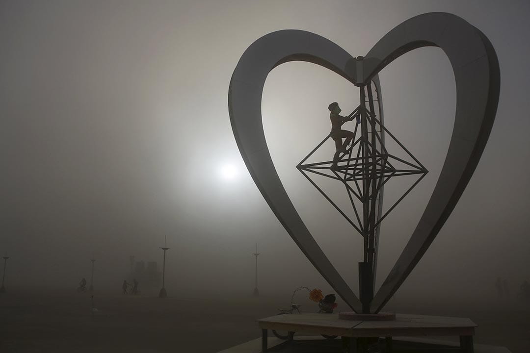 沙漠刮起沙尘暴，仍有参加者冒险攀上装置艺术品METAHEART。摄：Jim Urquhart/Reuters