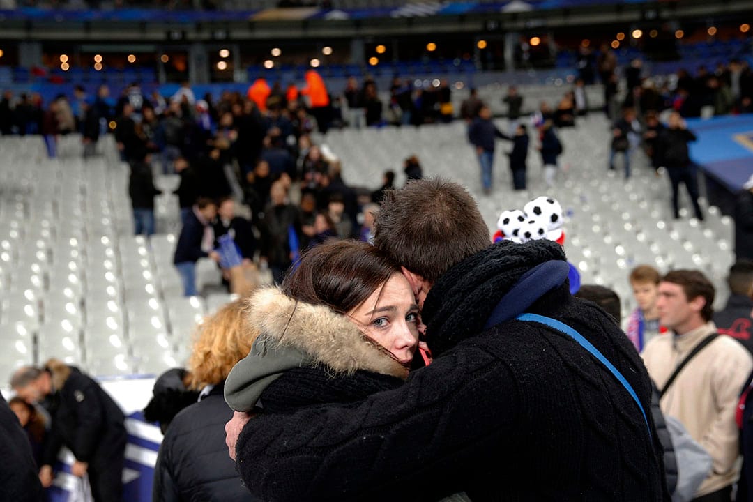 球场受袭后，两名观众相拥互相安慰。摄：Christophe Ena/AP