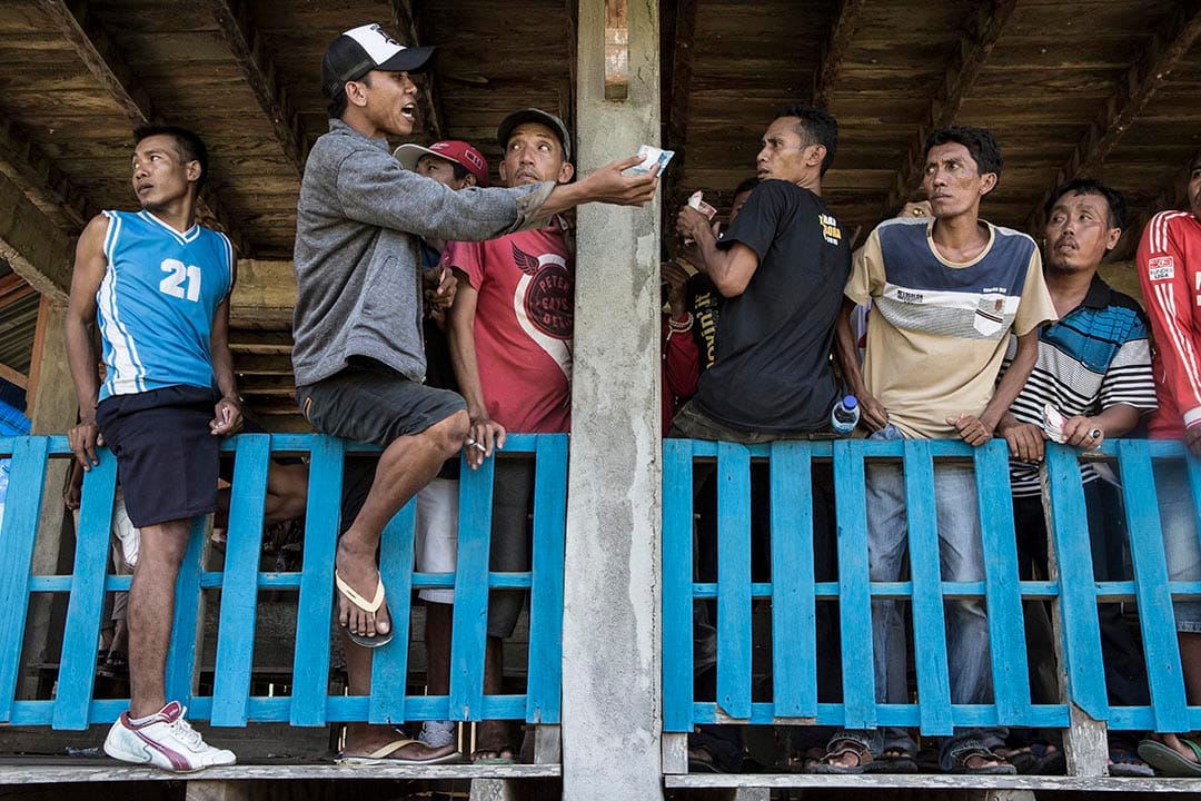 手持印尼盾的觀眾在場邊落注。攝:Putu Sayoga