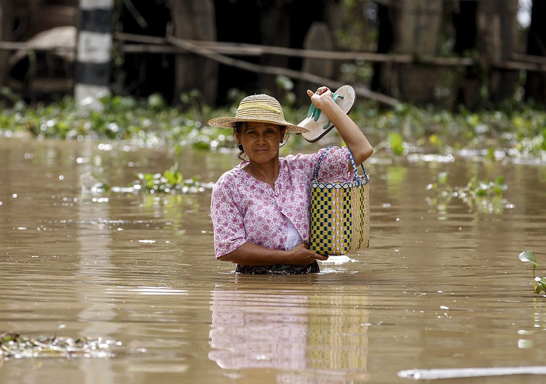 一名女士在灾区中涉水行走。摄: Soe Zeya Tun /REUTERS