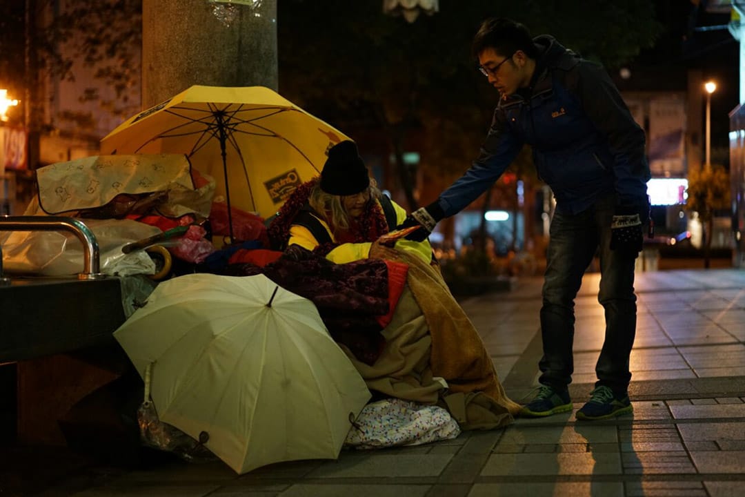 2016年1月24日,台北龙山寺,志工向街友派发物资及暖包。摄:张国耀/端传媒