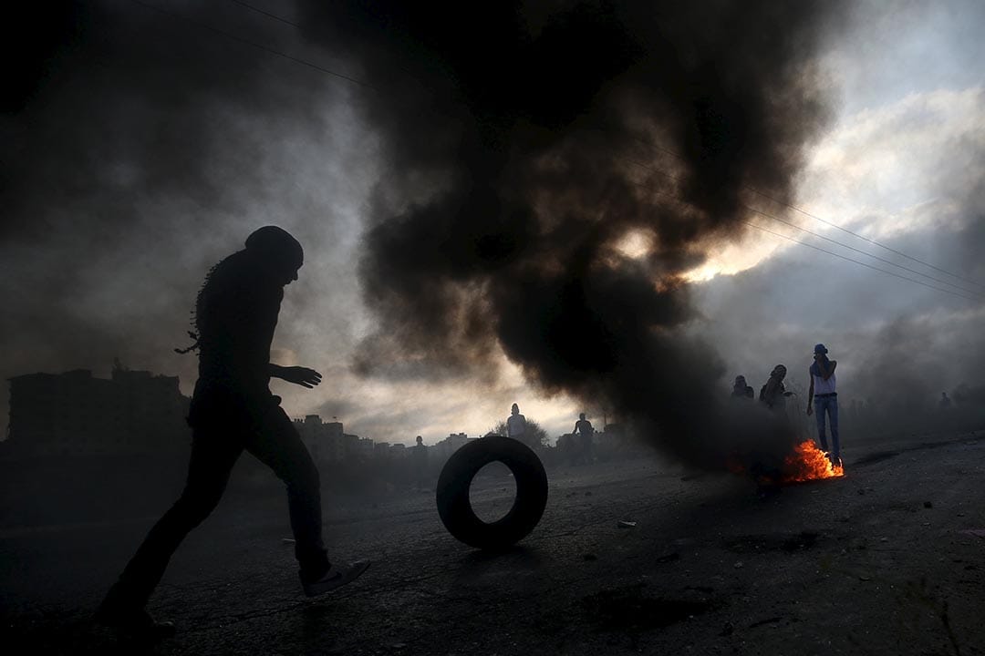 2015年10月5日約旦河西岸， 一名巴勒斯坦示威者滾動輪胎作為障礙物。 攝：Mohamad Torokman/REUTERS