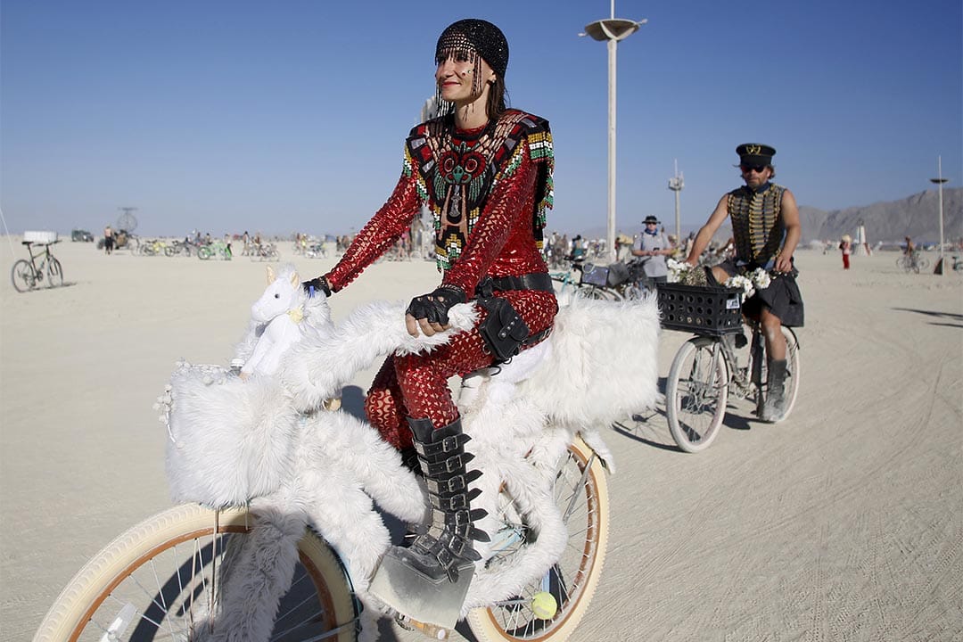 Burning Man（火人祭）参加者穿上盛装在场内踏单车。摄：Jim Urquhart/Reuters