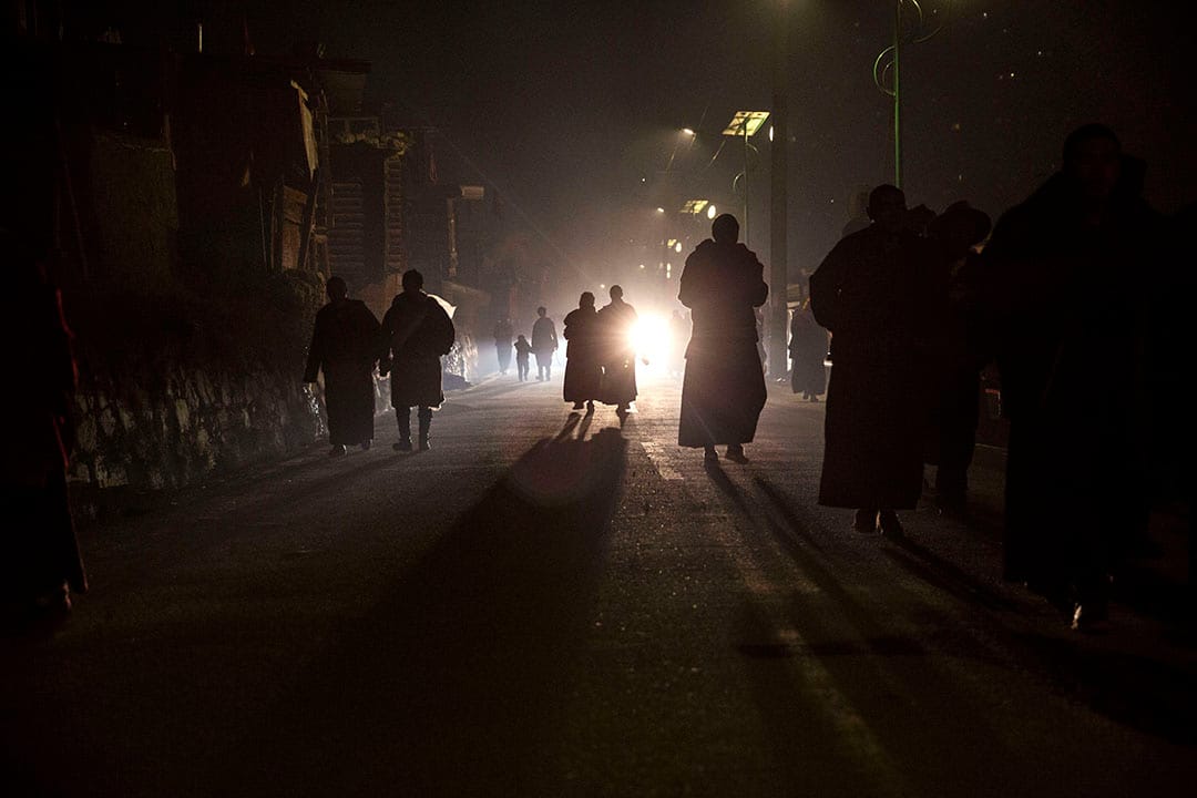 喇嘛們晚上離開佛學院,沿著黑暗的路回家。攝:Kevin Frayer/Getty Images
