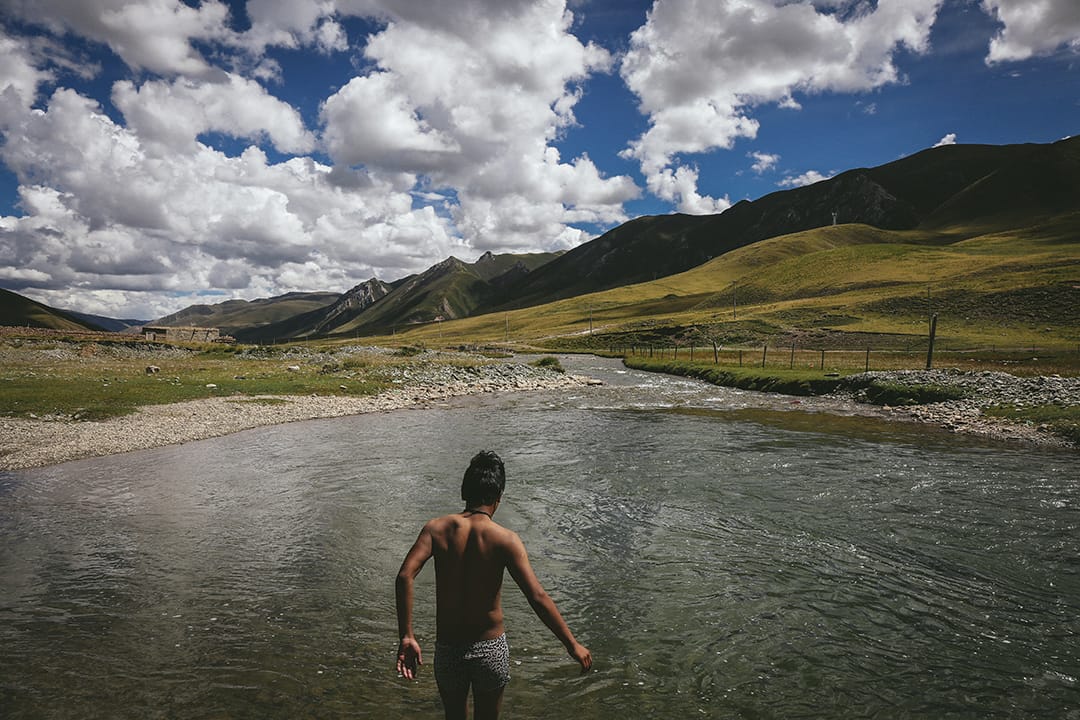 一名藏民青年在溪澗游泳。攝 : 王嘉豪/端傳媒