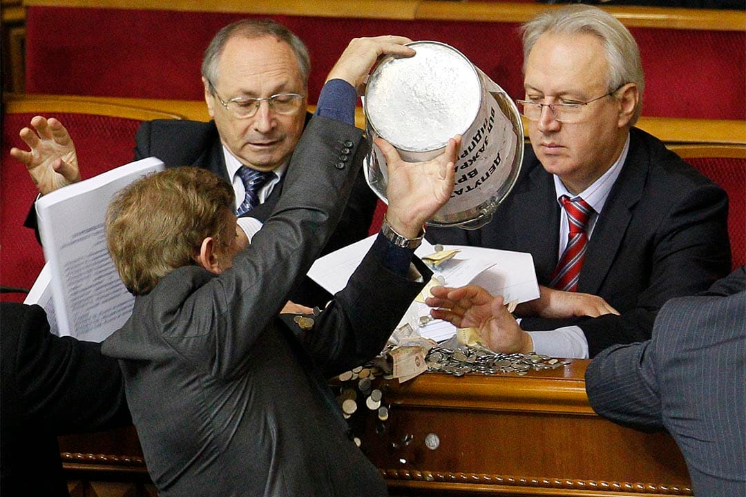 烏克蘭議員將一桶錢幣倒向一名政府官員。攝:Sergey Svetlitsky/REUTERS