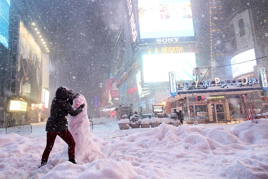 2016年1月23日，纽约时代广场，一名女子在行车路上堆砌雪人。摄：Yana Paskova/Getty Images