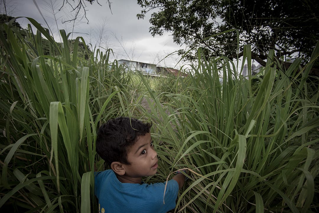 2014年，小孩的家位於比較偏遠的地區，在回家的路上四處張望。他母親是來自印尼的避難者，拿「行街紙」，他在香港出世，拿的也是行街紙。攝: Billy H.C. Kwok/ 端傳媒