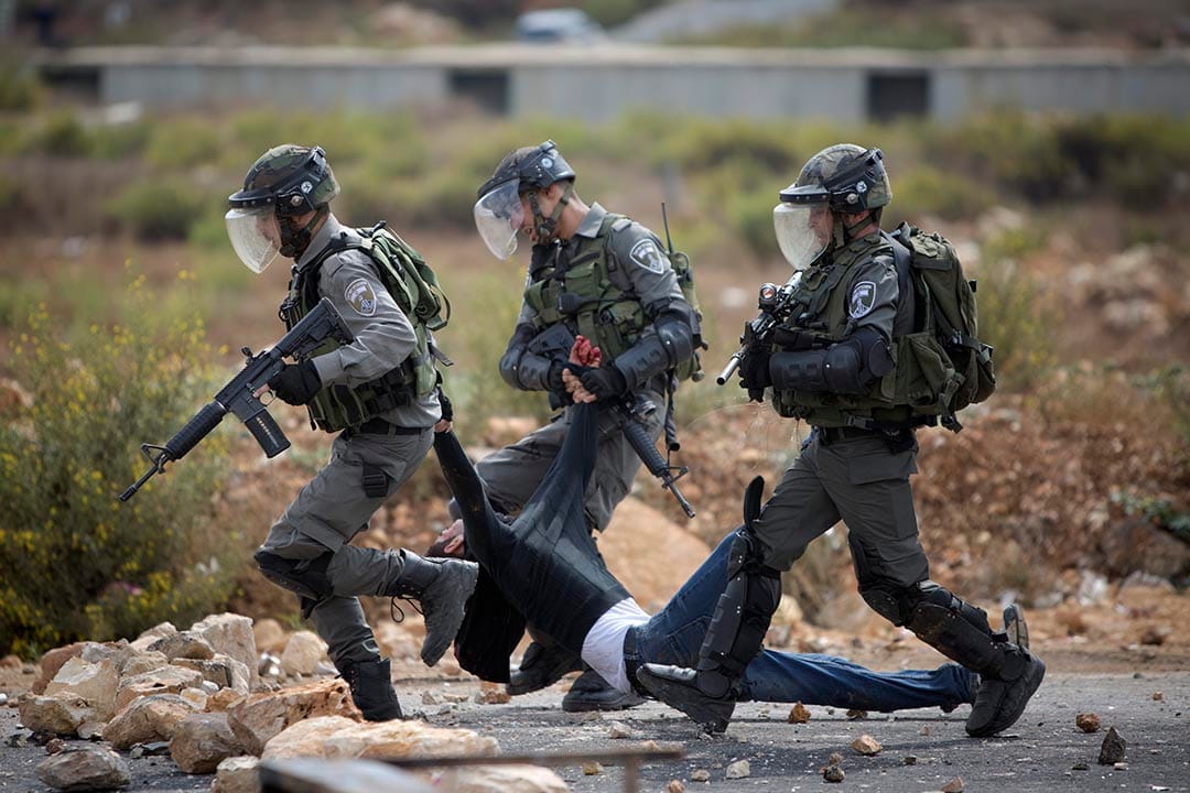 2015年10月7日，約旦河西岸城市拉姆安拉， 以色列軍人在衝突中攙扶一名受傷的巴勒斯坦男子。 攝：Majdi Mohammed/AP