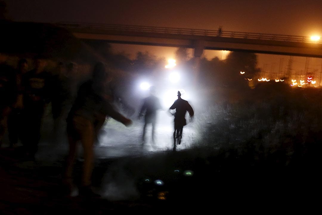 2015年8月5日 法國加來 警察手持電筒追捕企圖通過英法海底隧道偷渡的難民。攝: Juan Medina /REUTERS