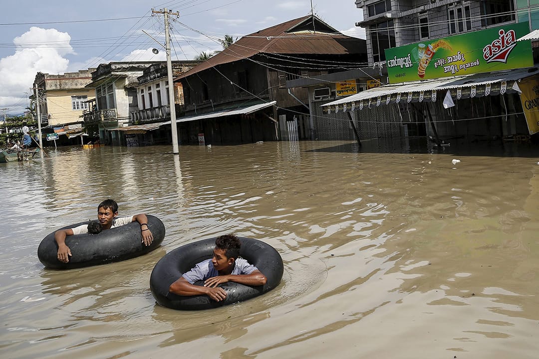 洪水淹没街道,灾民用水泡协助游出灾区。摄: Soe Zeya Tun/REUTERS